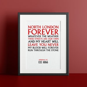 May include: A black framed print with white background and red text. The text reads "North London Forever" and includes the lyrics "Whatever the weather these streets are our own and my heart will leave you never my blood will forever run through the stone." The bottom of the print reads "Arsenal F.C. Est 1886."