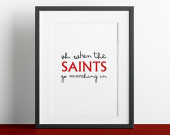 May include: Black framed print with white background and the text "oh when the SAINTS go marching in" in black and red lettering.