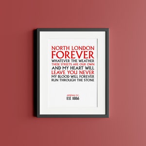 May include: A white framed print with black text that reads "North London Forever" and "Whatever the weather these streets are our own and my heart will leave you never my blood will forever run through the stone." The text is in red. The bottom of the print reads "Arsenal F.C. Est 1886".