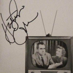 May include: Black and white image of a vintage television set with a couple on the screen. The word "Checkers" is at the top. A dog sits in front of the TV. There is an autograph on the left side.