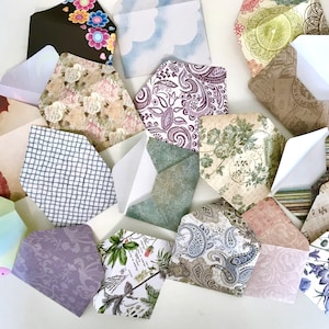 May include: Assortment of decorative envelopes with various patterns and colors, including floral, paisley, geometric, and musical note designs. The envelopes are made of paper and have a white interior.