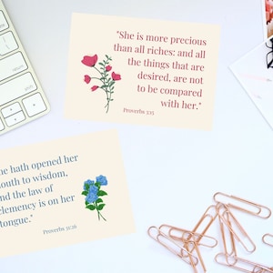 Puede incluir: Dos tarjetas imprimibles con citas inspiradoras de Proverbios 3:15 y 31:26. Las tarjetas presentan ilustraciones florales con flores rosas y azules.