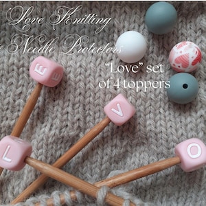 May include: Set of four pink silicone needle toppers with the letters "LOVE" in white. The toppers are on wooden knitting needles. The image also includes four additional silicone beads in various colours and patterns.