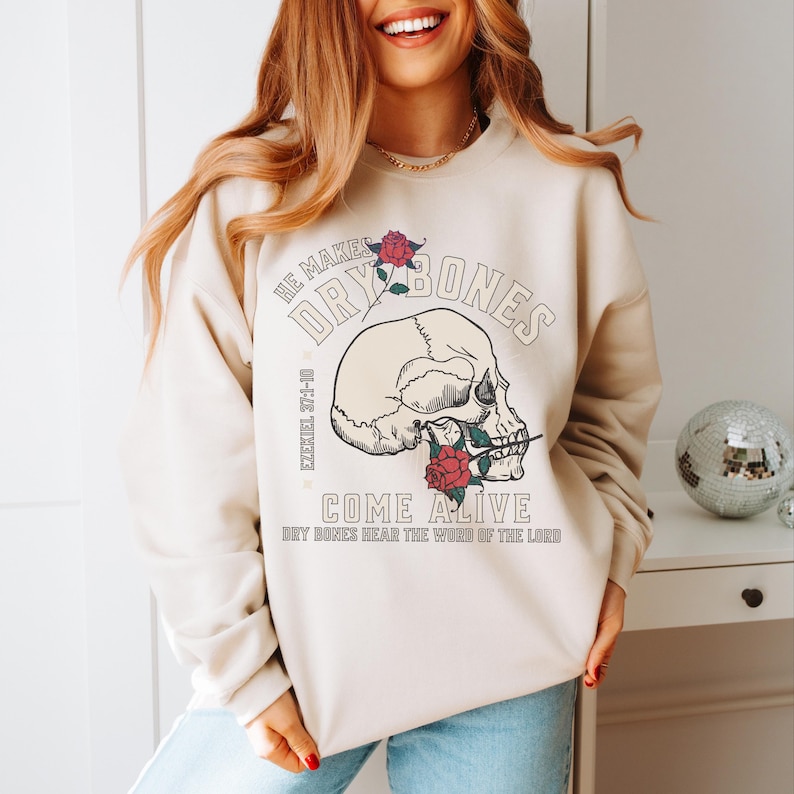 May include: A beige sweatshirt with a skull graphic and the text "He makes dry bones come alive Ezekiel 37:1-10 Dry bones hear the word of the Lord"