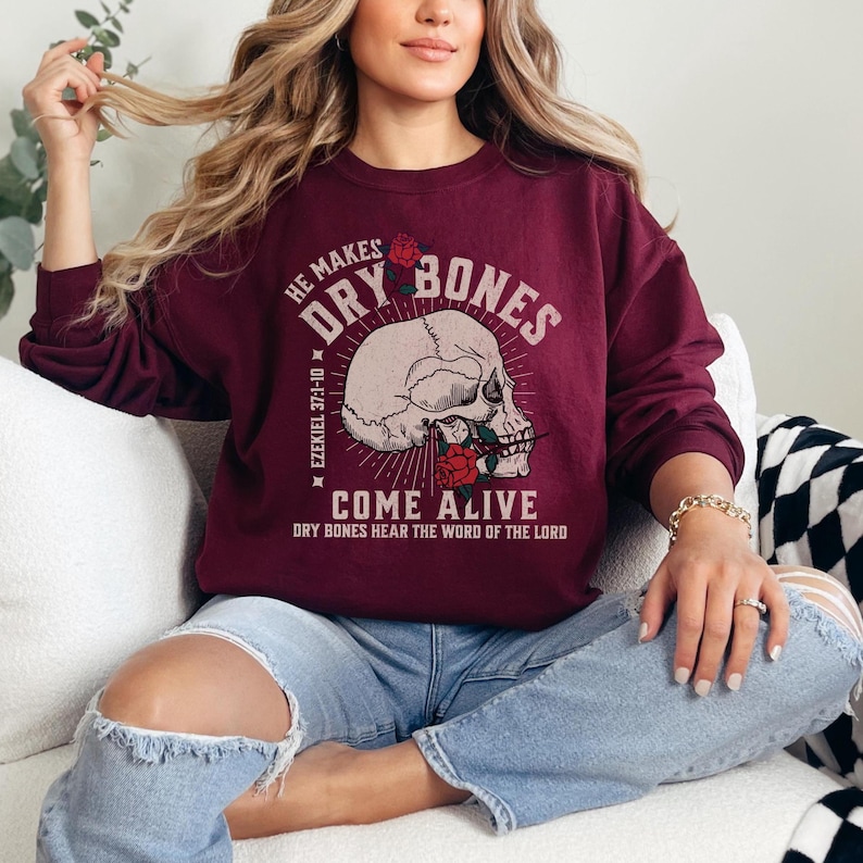 May include: A maroon sweatshirt with a skull graphic and the text "He Makes Dry Bones Come Alive" and "Ezekiel 37:1-10" and "Dry Bones Hear The Word Of The Lord".