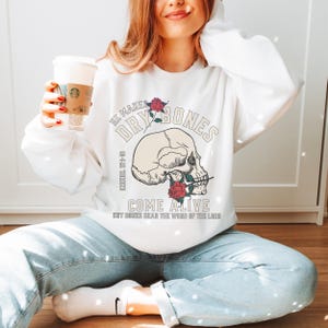 May include: White sweatshirt with a skull graphic and the text "He makes dry bones come alive dry bones hear the word of the Lord" printed on the front.