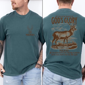 A teal t-shirt with a brown deer illustration and the text 'GET LOST IN THE MAJESTY OF GOD'S GLORY' on the back. The front of the shirt has a smaller deer illustration and 'PSALM 42:1'. Mens Christian Shirts, Bible Verse Shirt, Hunting Gifts, Husband Gift, Deer Hunter, Father's Day Gift, Jesus Shirt, Adult Baptism Gifts, Men's Shirt, Religious Shirt, Christian Gift, Religious Gift For Men, Hunting T-shirt, Deer Tshirt, Comfort Colors Tshirt