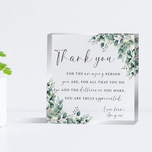 Puede incluir: Un bloque acrílico transparente con las palabras "Thank you" en escritura elegante. El bloque está decorado con hojas de eucalipto en acuarela y el mensaje "For the amazing person you are... You are truly appreciated."