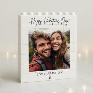 May include: A white block photo frame with a picture of a smiling couple. The frame has the text "Happy Valentines Day!" and "LOVE ALEX XX" with a heart symbol.