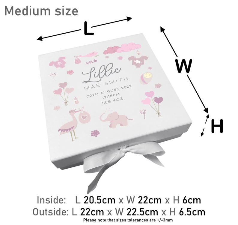 May include: A white gift box with a pink and white design featuring a stork, elephant, and balloons. The box is tied with a white satin ribbon. The box is labeled "Lillie Mae Smith" with the date "20th August 2022" and the time "12:15PM". The box measures 22 cm x 22.5 cm x 6.5 cm.