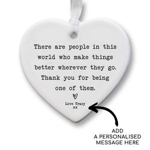 The image is a heart-shaped ornament with a personalized message attached to it. The message reads, "There are people in this world who make things better wherever they go. Thank you for being one of them." The ornament is personalized with the name "Love Tracy" and an arrow pointing to it. The message is a heartfelt expression of gratitude and appreciation.