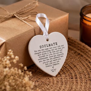 a heart-shaped tag with a romantic message, placed on a woven mat next to a brown candle.
