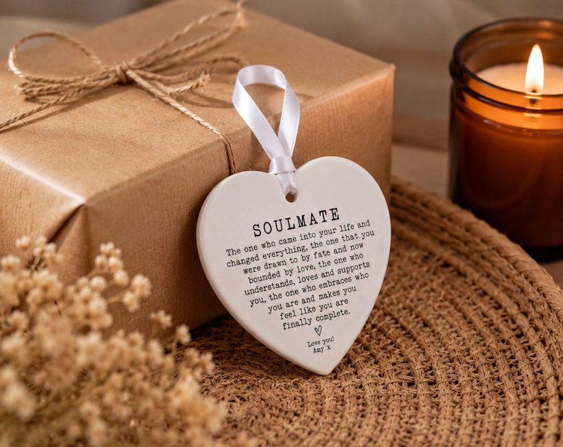 a heart-shaped tag with a romantic message, placed on a woven mat next to a brown candle.