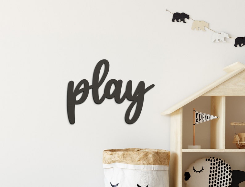 May include: Black wooden wall decor with the word "play" written in a cursive font.