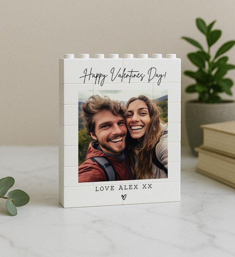 May include: A white block photo frame with the text "Happy Valentines Day!" and a photo of a smiling couple. The bottom of the frame reads "LOVE ALEX XX" with a heart symbol.