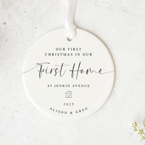May include: A white ceramic Christmas ornament with the text "Our First Christmas in Our First Home." The ornament includes the address "45 Jenkin Avenue," the year "2025," and the names "Alison & Greg."