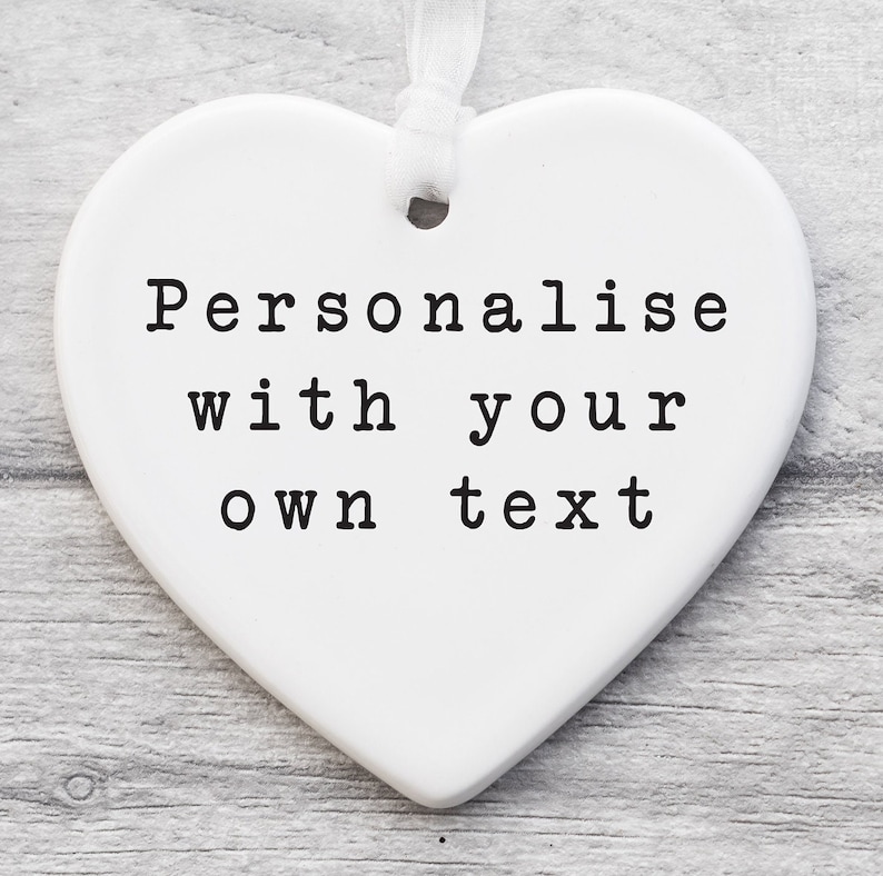 May include: White ceramic heart-shaped ornament with the text "Personalise with your own text" printed in black.