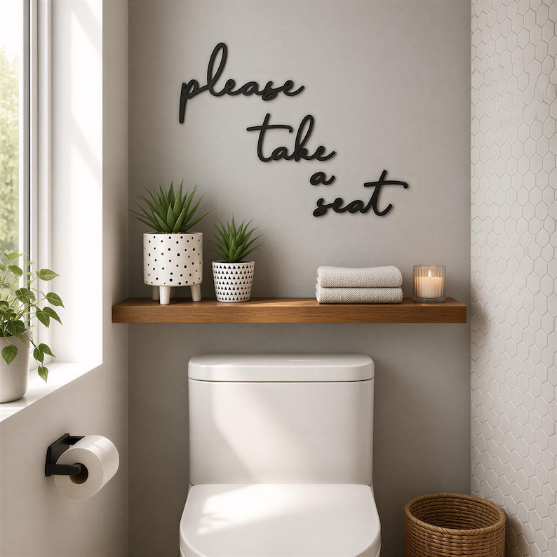 a bathroom with a white toilet, a wooden shelf above it holding a plant and towels, and a sign on the wall that says "Please take a seat".