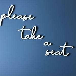 the text "Please take a seat" written in cursive on a blue background.
