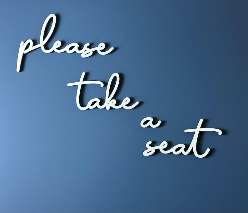 the text "Please take a seat" written in cursive on a blue background.