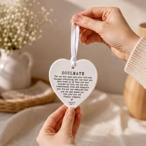 A person's hand holding a heart-shaped ornament with a message about love and relationships.