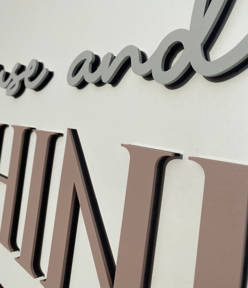 May include: Close-up of a brown and black sign with the words "House and Home" in a cursive font.