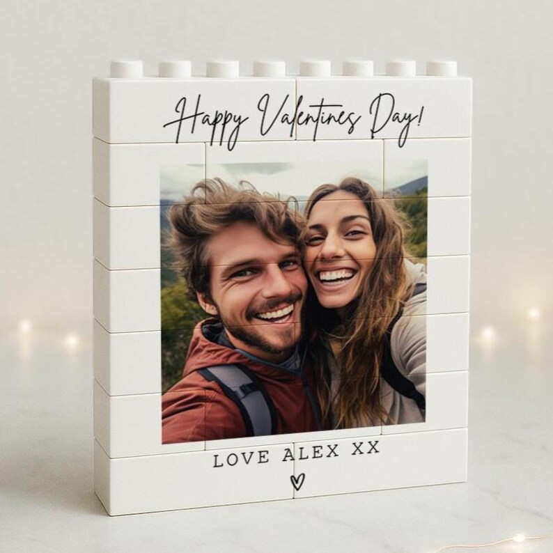 May include: White block photo frame with a picture of a smiling couple. The frame reads "Happy Valentines Day!" in black script. Below the photo, the text "LOVE ALEX XX" is written with a heart symbol.