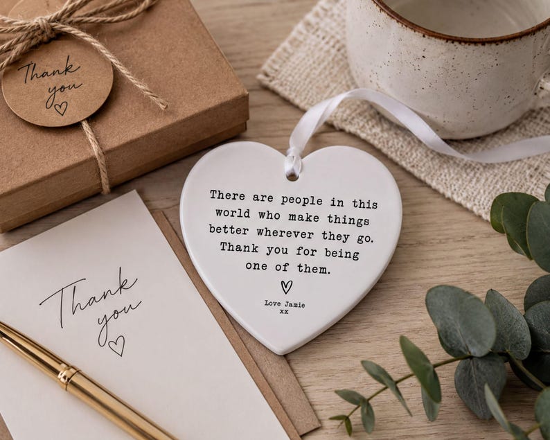 a heart-shaped ceramic ornament with a message, a note, and a mug on a wooden surface.