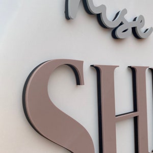 May include: A close-up of a sign with the word "muse" in a cursive font above the word "SHOP" in large, block letters. The letters are raised and have a black outline.