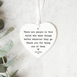 a heart-shaped ornament with a quote about people making things better where they go and being one of them.