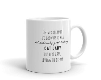 May include: White ceramic mug with black text that reads "I never dreamed I'd grow up to be a ridiculously good-looking cat lady but here I am, living the dream."