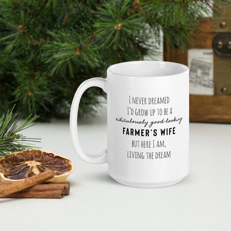 May include: White ceramic coffee mug with black text that reads: "I never dreamed I'd grow up to be a ridiculously good-looking farmer's wife, but here I am, living the dream."