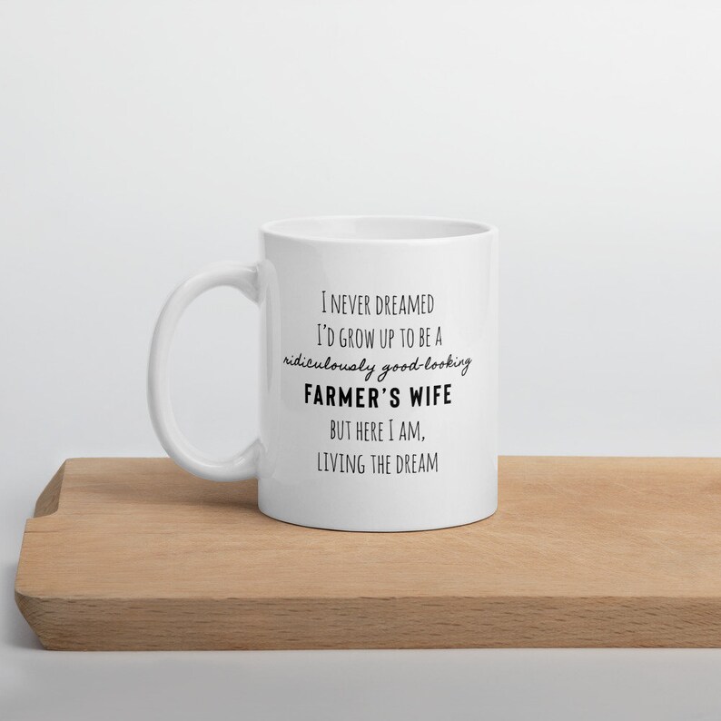May include: White ceramic mug with black text that reads: "I never dreamed I'd grow up to be a ridiculously good-looking farmer's wife. But here I am, living the dream."