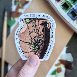 May include: A white sticker with a brown and green illustration of a cracked pot with plants growing out of it. The text "MY GRACE IS SUFFICIENT FOR YOU, FOR MY POWER IS MADE PERFECT IN WEAKNESS." is written around the illustration.