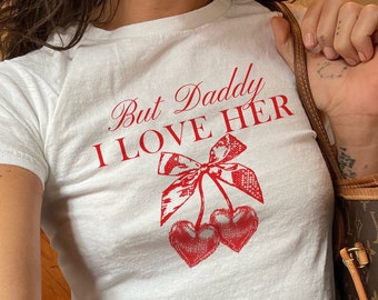 May include: White t-shirt with a red graphic that says "But Daddy I Love Her" and a red cherry design.