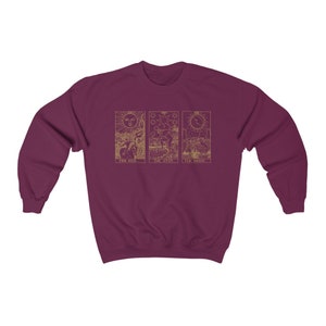 K&ouml;nnte beinhalten: Burgunderfarbenes Sweatshirt mit goldenen Tarotkarten-Designs: Die Sonne, Der Stern und Der Mond. Die Sonnenkarte zeigt eine Sonne mit Gesicht, die Sternenkarte eine Figur, die Wasser gie&szlig;t, und die Mondkarte einen Halbmond.