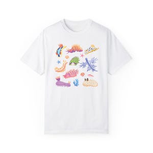 Pu&ograve; includere: Maglietta bianca con un'illustrazione colorata di varie lumache di mare. Le lumache di mare sono di forme e dimensioni diverse, con colori vivaci come rosa, blu, giallo e arancione.