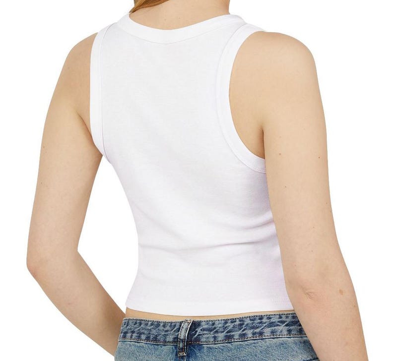 May include: A white, sleeveless crop top with a scoop neckline. The ribbed tank top is made of a soft material and is visible from the back. The bottom of the top is cropped, and the model is wearing blue jeans.