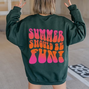 May include: A dark green sweatshirt with the text "Summer should be fun!" printed in pink and orange letters in a retro font.
