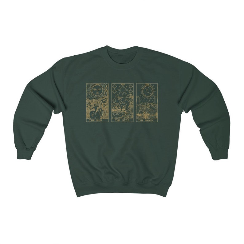 K&ouml;nnte beinhalten: Dunkelgr&uuml;nes Sweatshirt mit goldfarbenen Tarotkarten-Designs: Die Sonne, Der Stern und Der Mond. Das Sweatshirt hat einen Rundhalsausschnitt und lange &Auml;rmel. Die Tarotkarten-Bilder sind auf der Vorderseite zentriert.