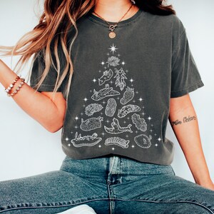 May include: Dark gray t-shirt featuring a white illustration of a Christmas tree made of various sea creatures and plants. The design includes starfish and other aquatic life. The shirt is a comfortable, casual style.
