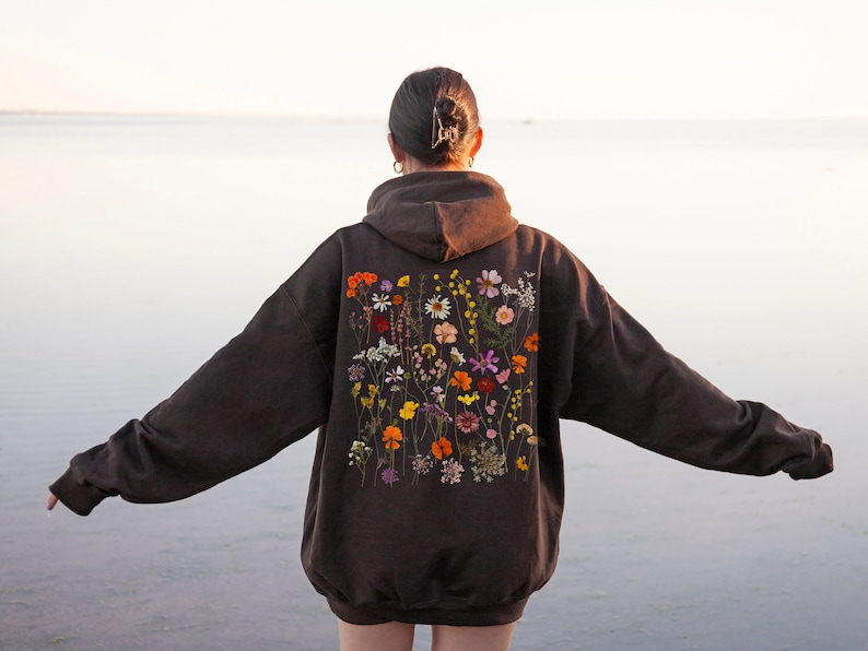 May include: A brown hoodie with a floral design on the back. The flowers are a variety of colors, including pink, yellow, orange, and purple.