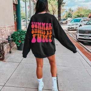 May include: A black sweatshirt with a pink and orange graphic print that says "Summer should be fun!" The graphic is in a retro, psychedelic font.
