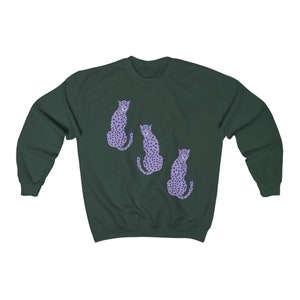 May include: A dark green sweatshirt with a graphic print of three purple cheetahs. The cheetahs are sitting down and facing different directions.