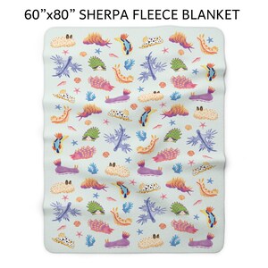May include: Sherpa fleece blanket, 60" x 80", featuring a repeating pattern of colorful sea slugs, coral, and starfish on a light blue background. The blanket's design includes various shades of orange, purple, green, and blue, creating a vibrant and whimsical aesthetic.