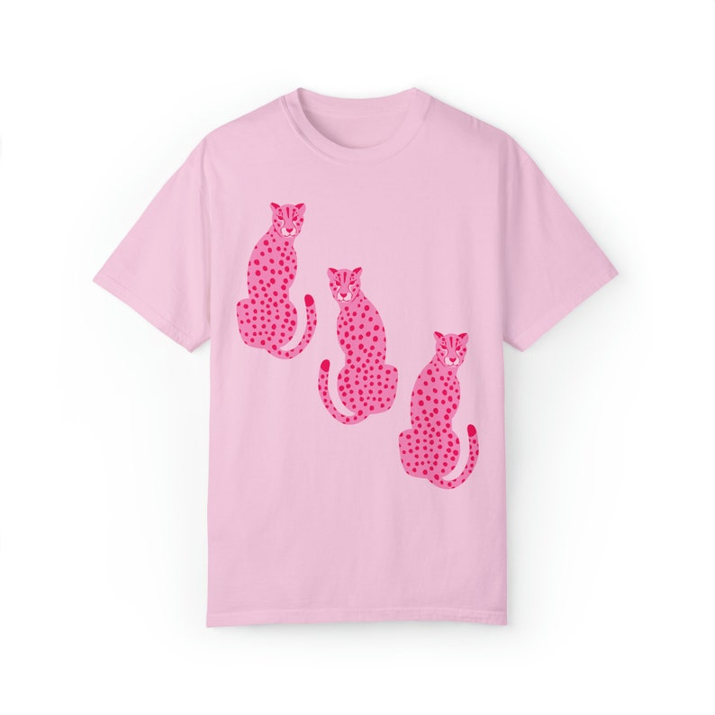 K&ouml;nnte beinhalten: Pinkes T-Shirt mit einem Motiv von drei pinkfarbenen Geparden mit schwarzen Flecken.