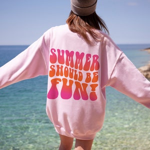 May include: Pink sweatshirt with the text "SUMMER SHOULD BE FUN!" in a retro, colorful font.