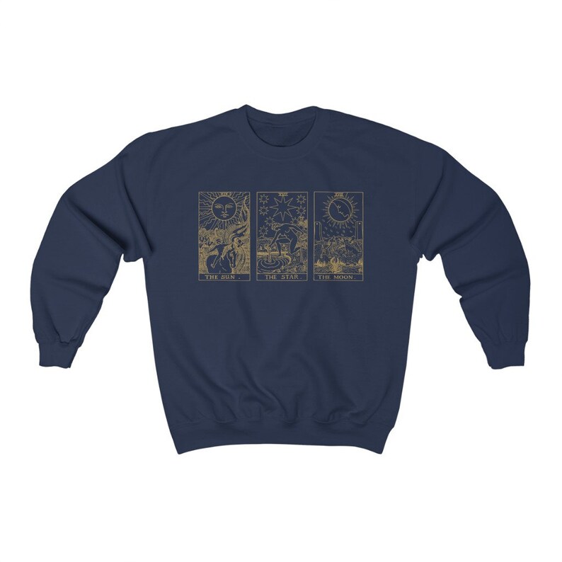 K&ouml;nnte beinhalten: Marineblaues Sweatshirt mit goldfarbenen Tarotkarten-Designs. Das Design zeigt die Karten Sonne, Stern und Mond. Das Sweatshirt besteht aus einem weichen Material und hat einen Rundhalsausschnitt.