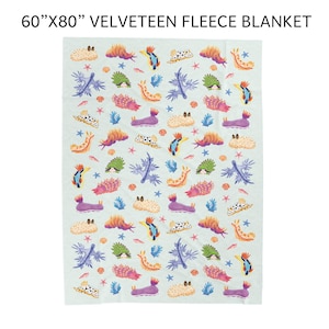 May include: A 60" x 80" velveeteen fleece blanket. The blanket features a repeating pattern of colorful sea creatures, coral, and starfish on a light blue background. The design includes orange, purple, green, and blue elements.