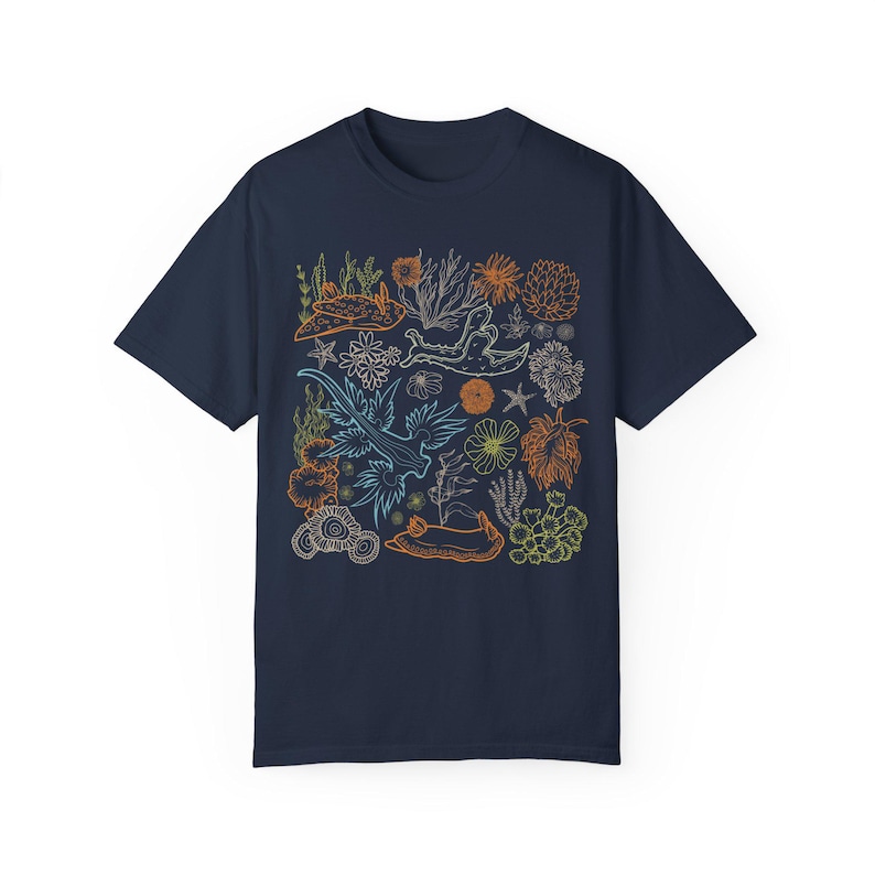 Pu&ograve; includere: Una t-shirt blu navy con un design grafico colorato di lumache di mare, coralli e altre forme di vita marina. Il design &egrave; delineato in bianco e presenta una variet&agrave; di colori, tra cui arancione, blu e verde.